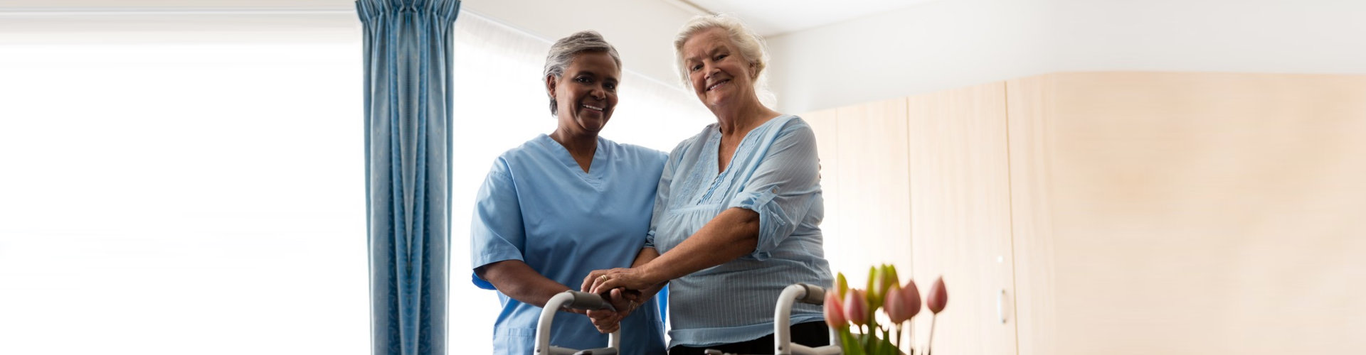 caregiver and senior woman holding her walking frame smiling